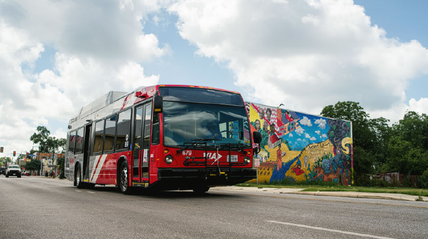 a bus drives past a mural on a cloudy day