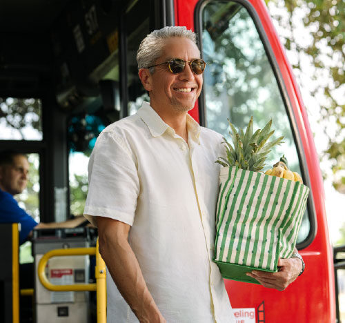 older man with groceries in hand alights the bus