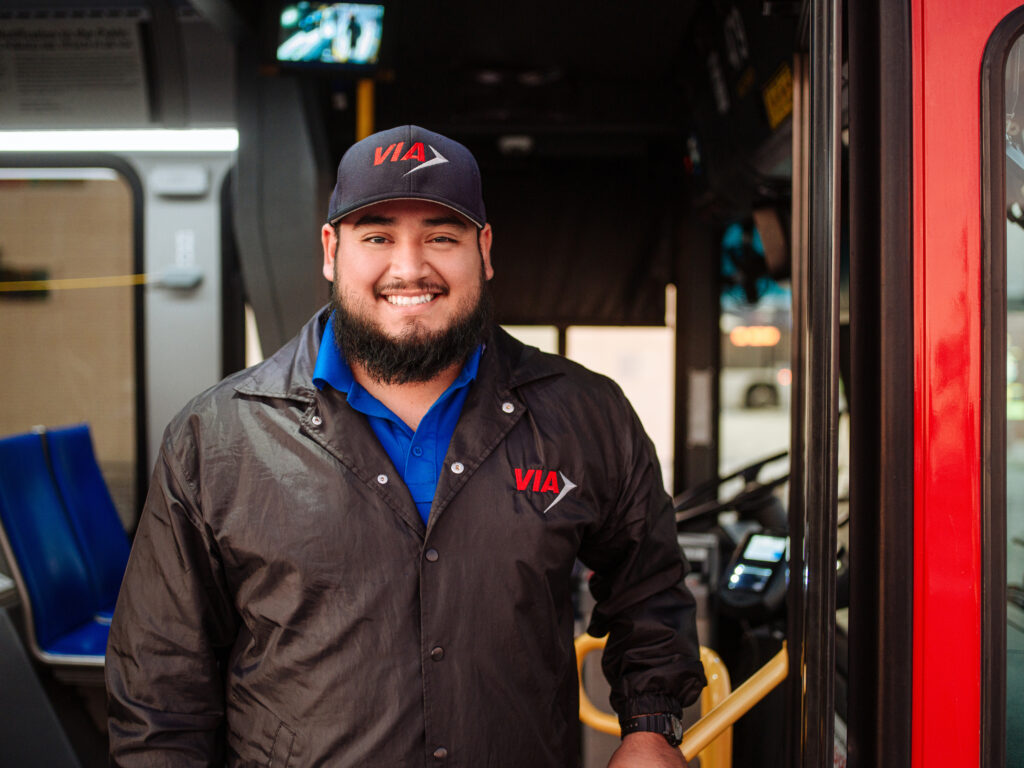 A VIA bus driver smiling in front of a bus